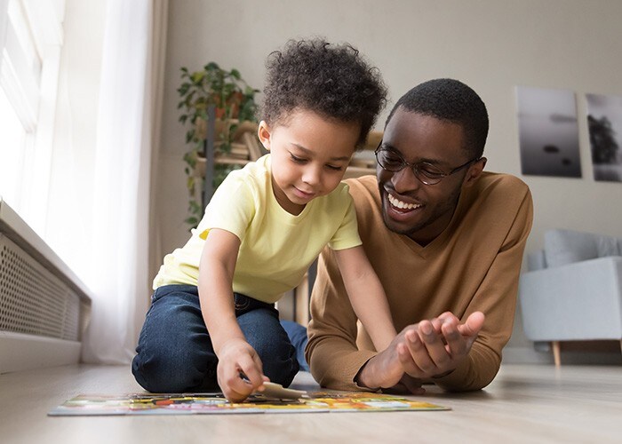 Father and little son playing jigsaw puzzle at home.