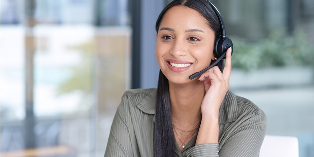 A woman talks on the phone while using her computer