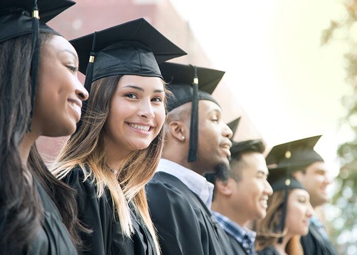 Des étudiants souriant à la cérémonie de remise des diplômes.
